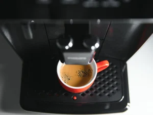 Imagen del surtidor de una cafetera superautomática, con una taza de café recién servida